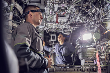 Obraz na płótnie Canvas Men mechanics is working inside the airplane