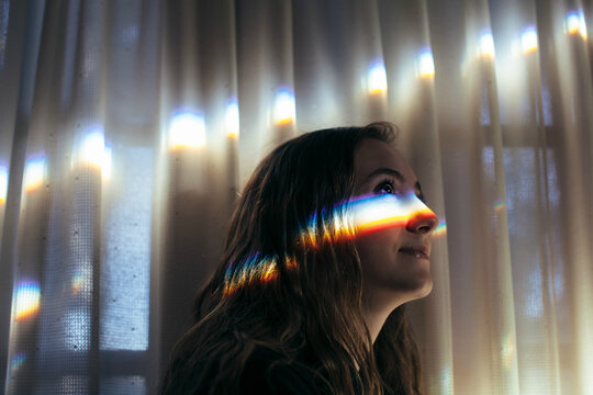 Teenage girl looking forward with a rainbow glowing prism on her face - Powered by Adobe