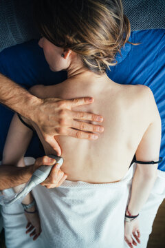 Young woman lying on her front having a muscular ultrasound check during a physiotherapy session