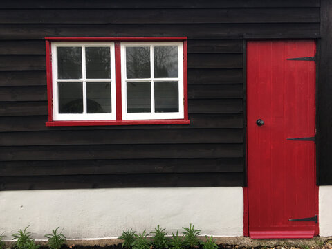 Outbuilding with red door and window frames.