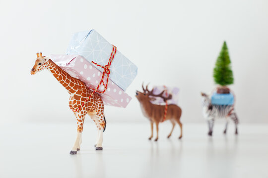 Toy animals carrying Christmas gifts on white.