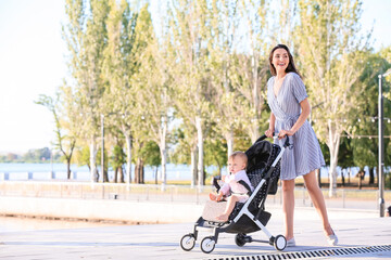 Woman and her cute baby in stroller outdoors