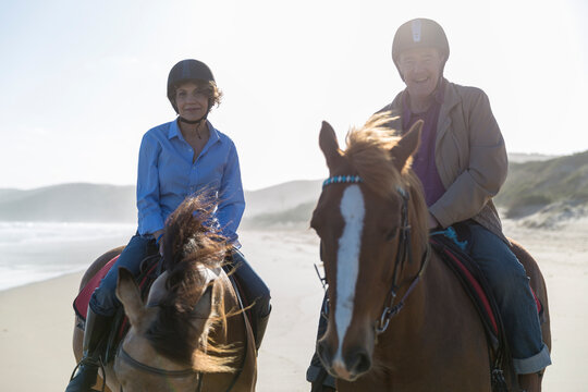 Senior male and female riding horseback laughing and looking into camera
