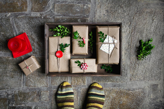 Feet with warm winter socks standing in front of Christmas gifts