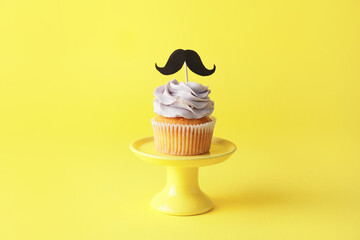 Tasty cupcake with stylish topper on color background
