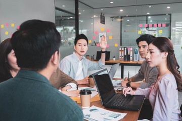 Focus on young asian man having question in group brainstorm meeting in office.Businesspeople discussing with paperwork for business plan,Corporate of modern colleague