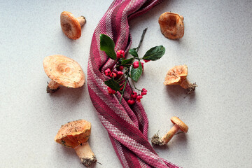 Freshly picked redheads with a striped napkin and a branch on the kitchen table, top view, close-up, the concept of using mushrooms in cooking