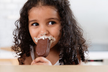 Cute little girl messily eating ice cream bar