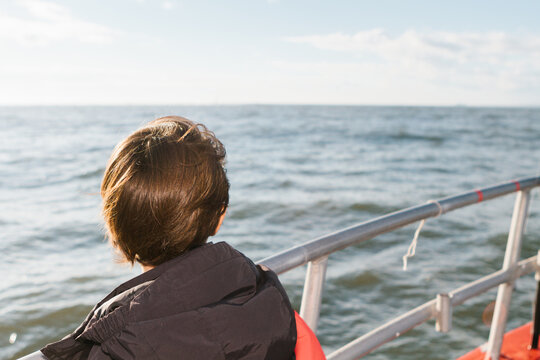 Young boy on a boat looking out at sea