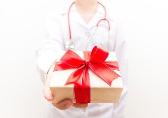 Doctor holding the gift box with red ribbon and bow in her hand. Female doctor. Selective soft focus