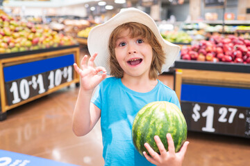 Fototapeta premium Portrait of child hold watermelon in grocery shopping in supermarket, Concept of shopping, healthy food, sell and buy.