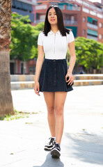 Portrait of young smiling girl in lightweight dress walking through downtown streets. High quality photo