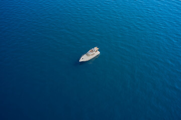 White big yacht anchored on blue water. Drone view of a boat  the blue clear waters. Aerial view luxury motor boat.