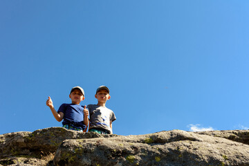 Fototapeta na wymiar Two small children, brothers boys standing on one rocky peak, a mountain of Carpathian mountains, happy children, children on a hike.