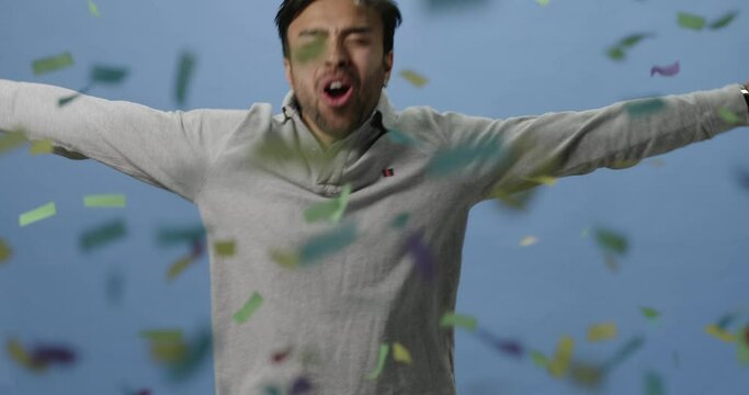 Slow motion, happy man jumps with joy and celebrates with confetti