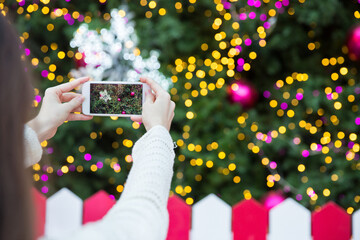 Woman taking a photo of a Christmas tree