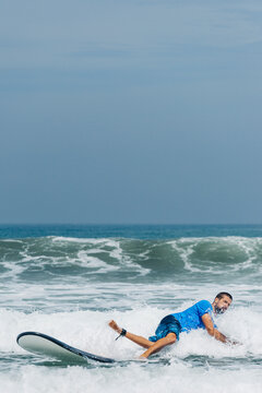 Young man falling in water while learning to surf the waves