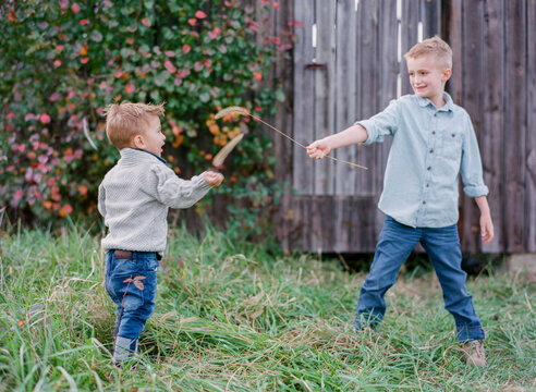 Brothers sword fighting with fuzzy weeds