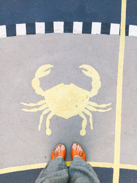 Looking down in a woman's feet wearing orange sandals