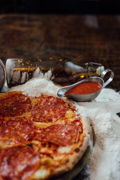Sausage pizza arranged with olive bottle and tomato sauce