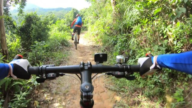 Two friends cross country mountain biking in tropical forest. POV point of view .4k  
