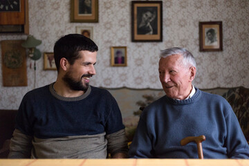 Grandpa and his grandson sitting at the table talking and laughing