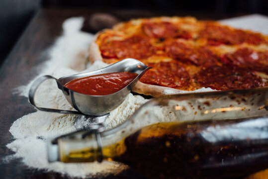 Sausage pizza arranged with olive bottle and tomato sauce
