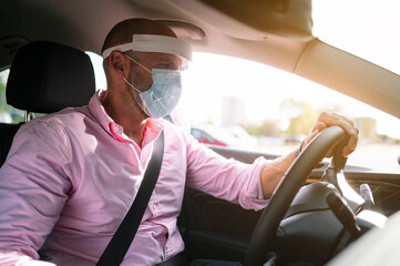 Man driving car with protective mask