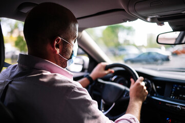 Man driving car with protective mask