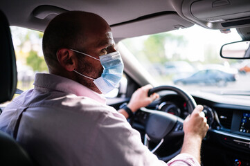 Man driving car with protective mask