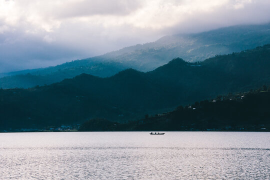 Boat on a lake with light rays and mountains. Travel image in Pokhara, Nepal