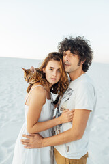 Beautiful couple of lovers hug each other and hold the cat in their arms