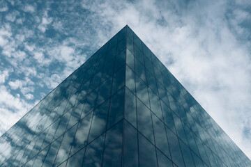 Low angle view of modern office building and sky, clouds reflecting in windows