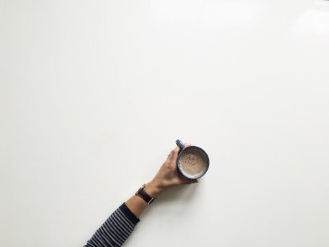 Overhead image of someone holding a cup of tea.