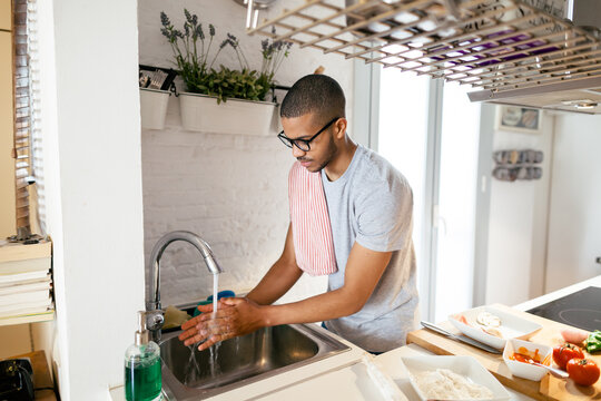 Latin man washing hands in the kitchen.