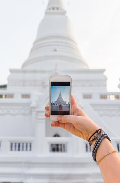 Hand with phone taking photo of Wat Patum /royal buddhist temple in Bangkok /Thailand
