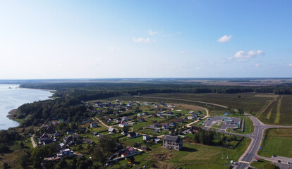 Top view of suburban cottages and houses near a large summer lake