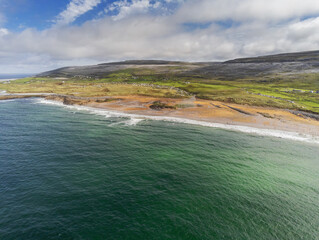 Aerial drone view on Fanore beach, county Clare, Ireland. Warm sunny day, People on the beach and surfing in the water. Cloudy sky, Popular surfing spot. Part of Wild Atlantic Way route.