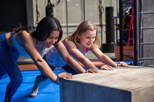 Two fit girls pushing a plyo box