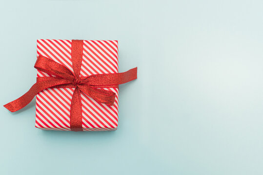 Small red and white wrapped gift on blue - wide