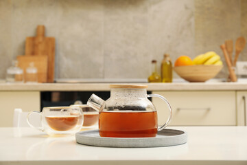 Fototapeta na wymiar Glasses and pot of tea against kitchen interior