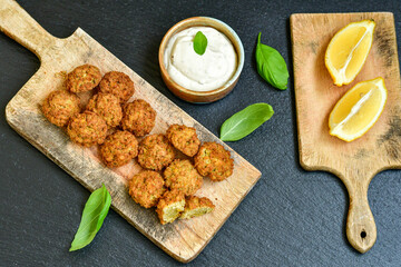 Fresh vegan dish-  falafel balls from spiced chickpeas  with lemon   and garlic yogurt sauce  on wooden rustic table.