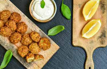Fresh vegan dish-  falafel balls from spiced chickpeas  with lemon   and garlic yogurt sauce  on wooden rustic table.