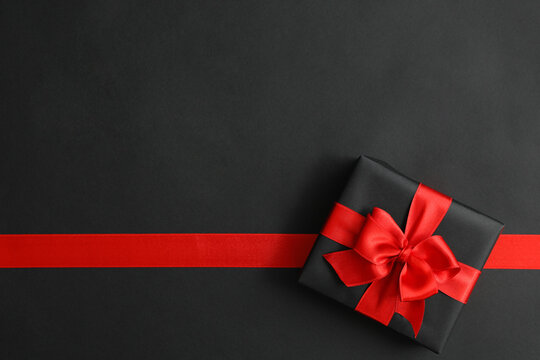 Gift box and red ribbon on black background