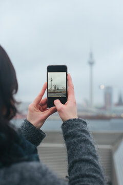 Detail of Woman Taking Smartphone Photo of Berlin's TV Tower on Rainy Winter Day
