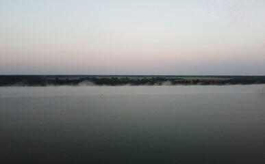Fototapeta na wymiar Top view of fog at sunrise over calm lake and forest