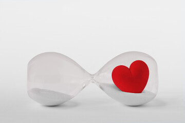 Hourglass with heart lying on white background - Concept of time and love