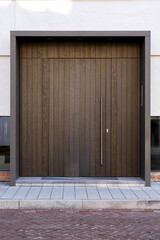 Massive wooden entrance door to modern white house with paving footpath in the city. New, modern architecture, exterior design