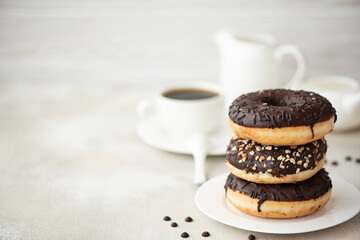 a stack of chocolate glazed donuts with coffee and milk
