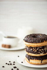 a stack of chocolate glazed donuts with coffee and milk